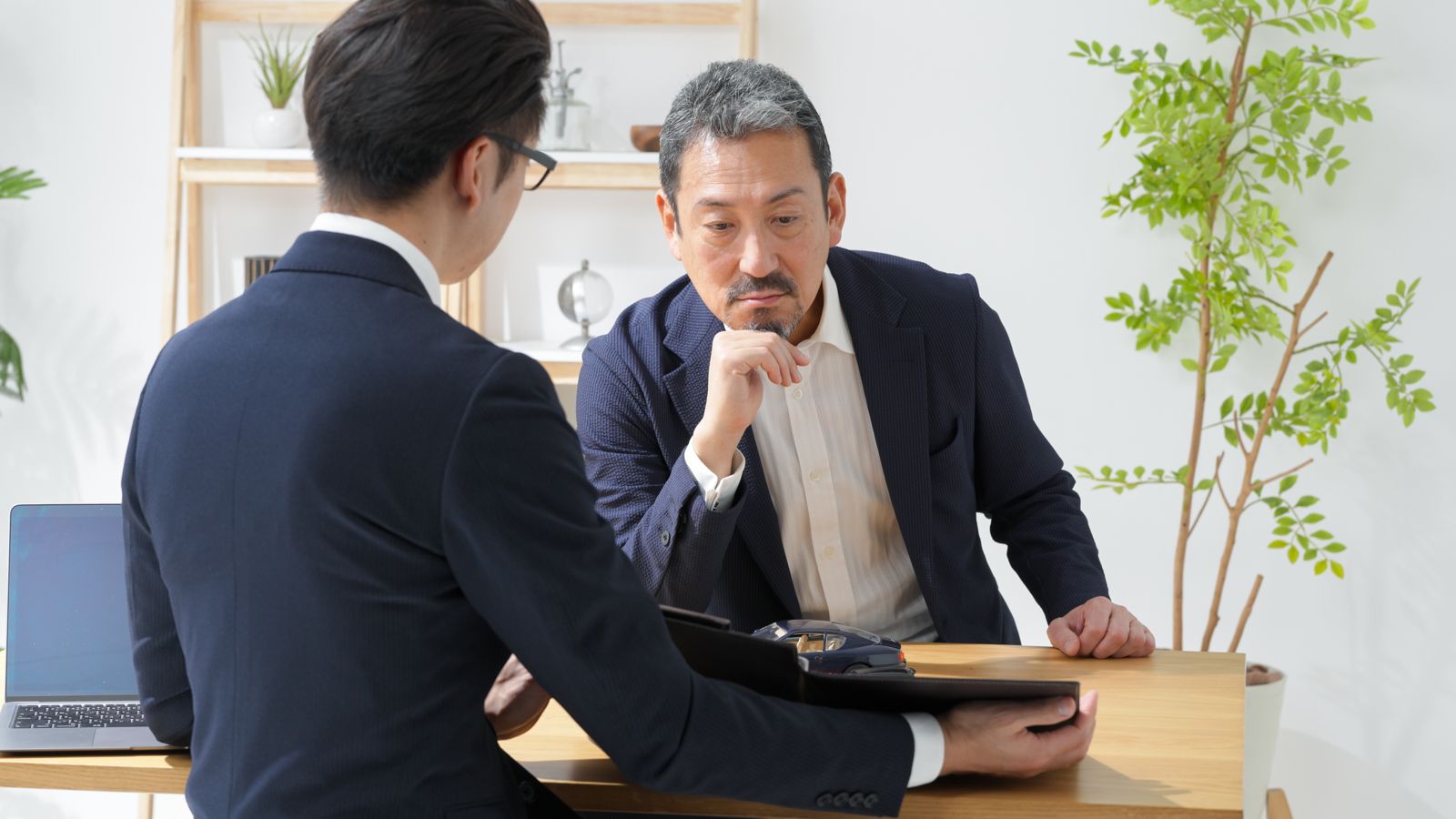 打ち合わせで経営者の話を聞くコンサルタント